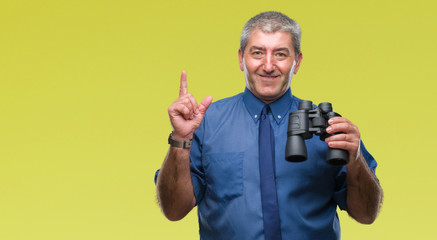 Handsome senior man looking through binoculars over isolated background surprised with an idea or question pointing finger with happy face, number one