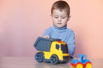 A cute little boy playing with model car collection. Toy mess in child room.