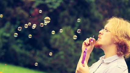 man blowing soap bubbles, having fun
