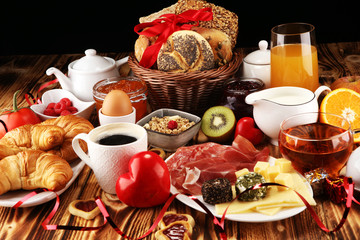 breakfast on table with bread buns, croissants, coffe and juice on valentines day.