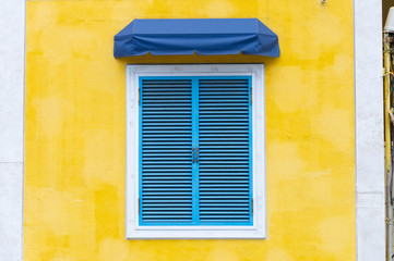 Fototapeta na wymiar yellow wall of the house with a closed window and details.