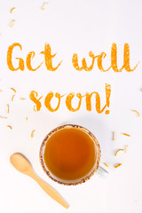 Get well soon - written from ground turmeric on a white background among the products for the treatment of common cold - lemon, honey, ginger