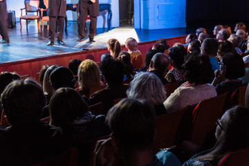 Spectators at a theater performance, in a cinema or at a concert. Shooting from behind. The...