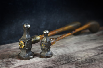 two old vintage hammers from a goldsmith on a wooden workbench against a dark background with copy space, close up