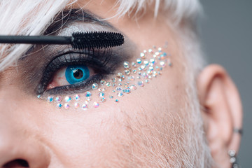 Rethink your lash look. Male makeup artist. Transgender man apply mascara. Male makeup look. Transgender man wear eyeshadows and eyebrow makeup. Fashion male eye makeup © Volodymyr