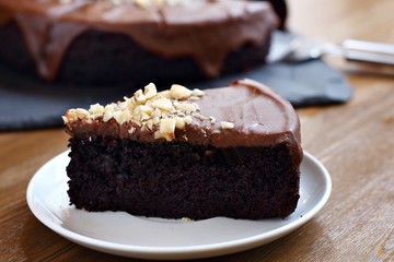 Chocolate cake with glaze and nuts on white plate