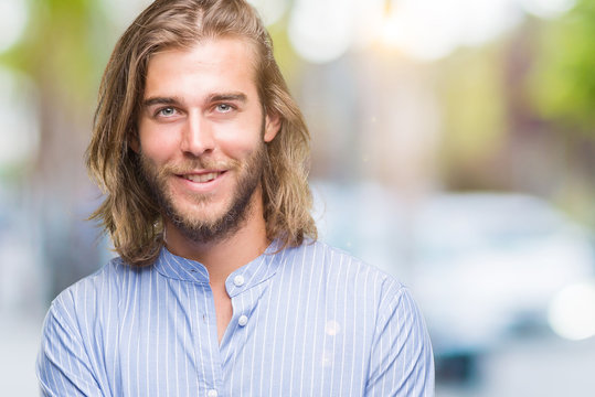 Young handsome man with long hair over isolated background happy face smiling with crossed arms looking at the camera. Positive person.