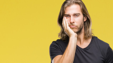 Young handsome man with long hair over isolated background thinking looking tired and bored with depression problems with crossed arms.