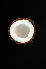 one half of ripe coconut on black background,top view
