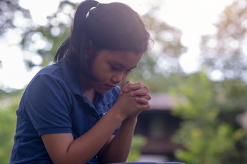 Asian child praying and hopeful for peace the world.Little kid sitting and hands in hands together...