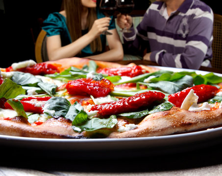 Pizza with dried tomatoes, rucula and mozzarella in pizzeria