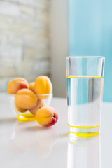 Clean drinking water in a glass, a bowl of apricots on the table. Healthy food. Vertical