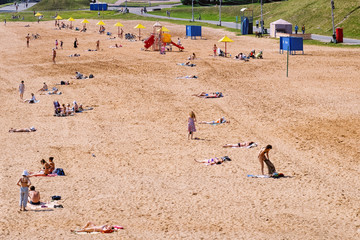 Fototapeta na wymiar People sunbathing on sandy beach at Volkhov River Veliky Novgorod