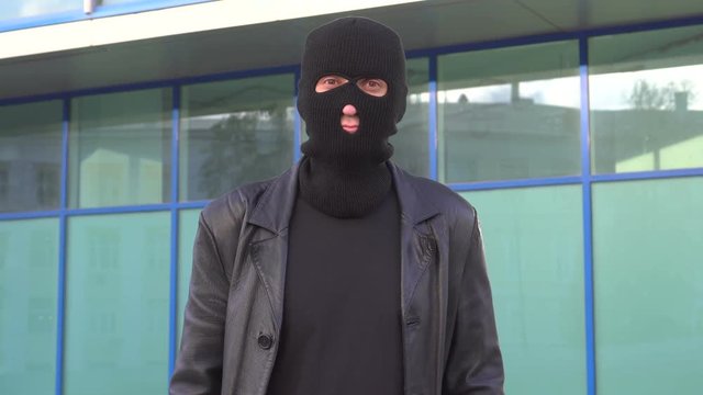 Man in the mask standing outdoor. Robber, bully, hoodlum, thug, ruffian