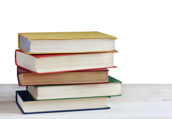 Pile of books in color covers on table isolated on white background.