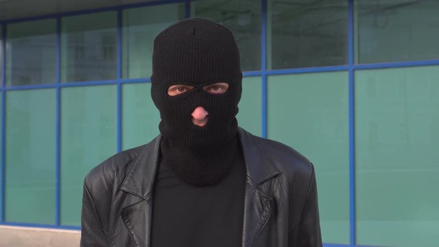 Criminal man thief or robber in mask looking at camera