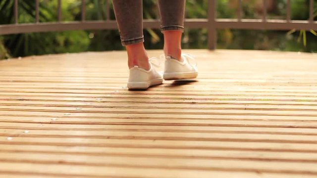 Close up woman legs in white shoes back view on balcony determined direction feet happy healthy jeans journey keds lifestyle person living outside road slow motion