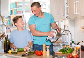 Man with his son are cooking soup in the kitchen