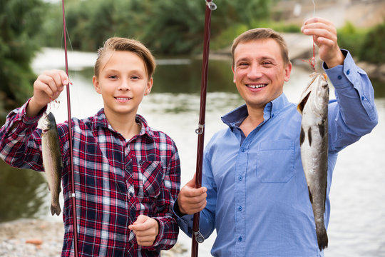 Young father with son looking at fish on hook