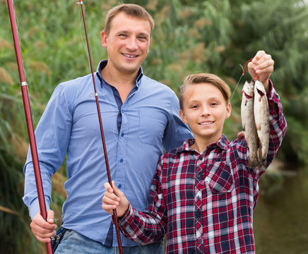 Glad father with son looking at fish on hook