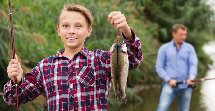 Positive teenage boy releasing catch on hook fish