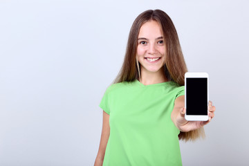 Fototapeta premium Beautiful girl with smartphone on grey background