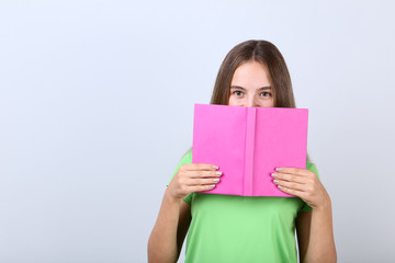Fototapeta premium Young girl with book on grey background