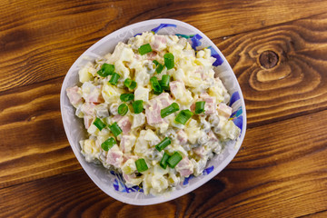 Traditional Russian festive salad Olivier on wooden table. Top view