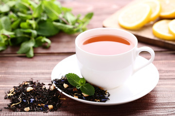 Cup of tea with mint leafs on brown wooden table