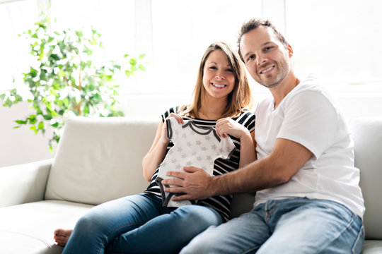 A pregnancy and people concept happy man pregnant woman at home clothes looking