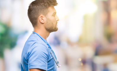 Young handsome doctor surgeon man over isolated background looking to side, relax profile pose with natural face with confident smile.