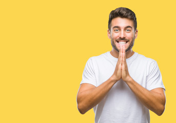 Young handsome man over isolated background praying with hands together asking for forgiveness smiling confident.