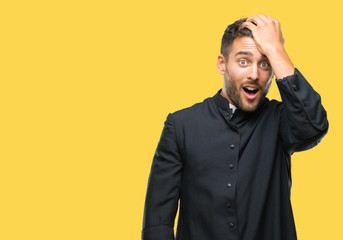 Fototapeta premium Young catholic christian priest man over isolated background surprised with hand on head for mistake, remember error. Forgot, bad memory concept.