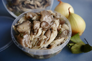 Marinated mushrooms with butter in a plastic container