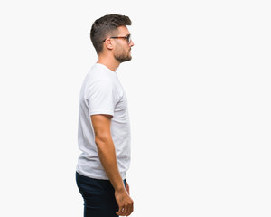 Young handsome man wearing glasses over isolated background looking to side, relax profile pose with natural face with confident smile.