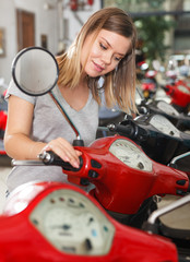Fototapeta na wymiar Woman is shopping and choosing new motobike