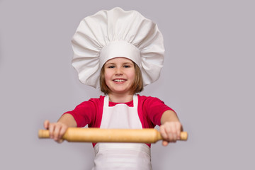 Children cook. Happy little girl in chef uniform holds rolling pin isolated on white background.