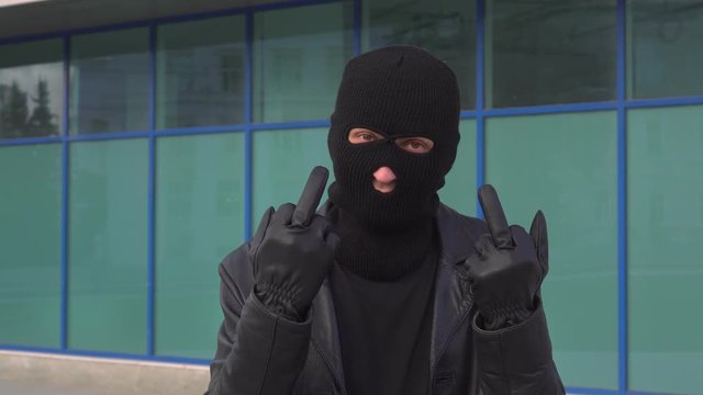 Criminal man thief or robber in mask showing middle finger at camera.