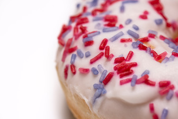 Macro of a donut with blue sprinkles on a white plate