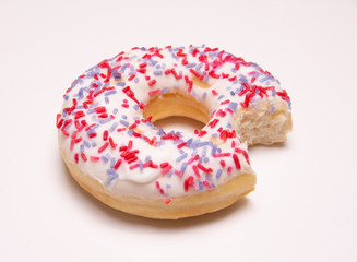 closeup of a donut with frosting and a bite taken out on a white background