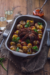 Octopus tentackes with baked potatoes and sauce in a tray