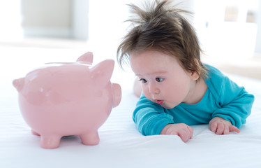 Baby boy with a piggy bank in childcare costs or savings theme