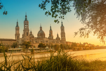 Basilica Cathedral of Our Lady of Pillar and bridge over Ebro River at sunset in Zaragoza, Aragon, Spain. Famous tourist landmark