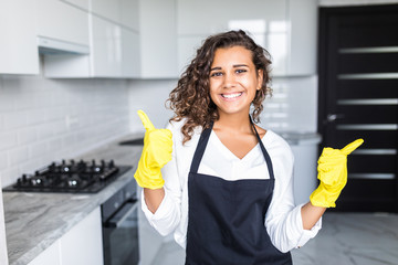Smiling young latin cleaning lady with pink rubber gloves showing ok sign with thumbs up in the...