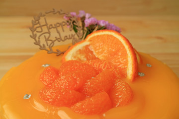 Closed Up Vibrant Color Delicious Mandarin Orange Birthday Cake on the Wooden Table 