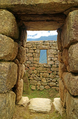 Ancient doorway with the remains of the Incas and the mountain ranges, Machu Picchu, Cusco, Peru 