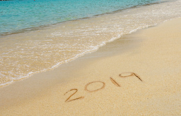 2019 written in sand write on tropical beach