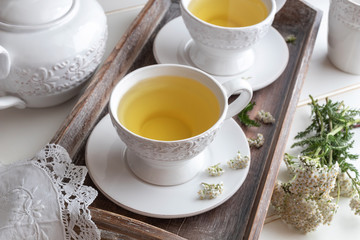 Yarrow tea in white cups with fresh yarrow plant