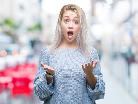 Young blonde woman wearing winter sweater over isolated background afraid and shocked with surprise expression, fear and excited face.