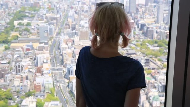 Aerial view of Osaka skyline in Japan. Young caucasian tourist woman looking Osaka cityscape from the observation deck. Travel and tourism asia concept.